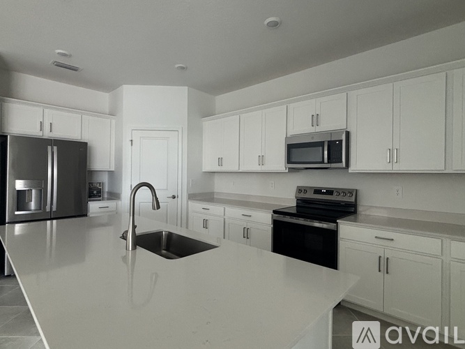 A modern kitchen with white cabinets and appliances.