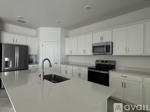 A modern kitchen with white cabinets and appliances.