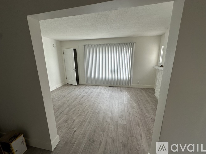 A room with wooden flooring and a window with blinds.