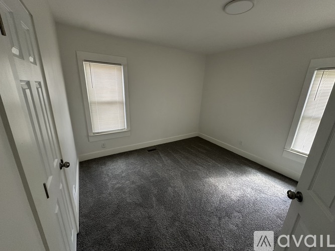 A room with a carpeted floor and two windows.