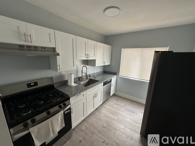 A kitchen with a stove, sink, and cabinets.