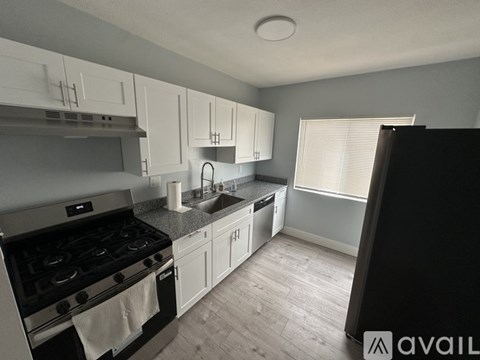 A kitchen with a stove, sink, and cabinets.