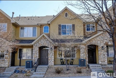 A two-story house with a stone exterior and a dark brown door.