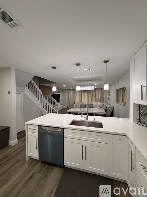 A modern kitchen with white cabinets and a wooden floor.