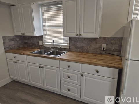 A kitchen with white cabinets and a wooden countertop.