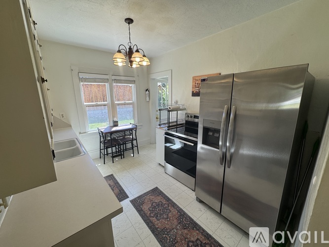 A kitchen with a refrigerator, sink, and dining table.
