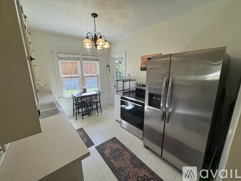 A kitchen with a refrigerator, sink, and dining table.