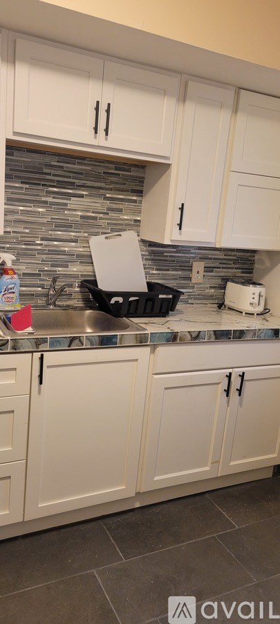 A kitchen with white cabinets and a stone backsplash.