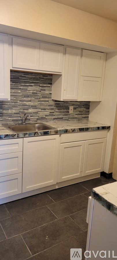 A kitchen with white cabinets and a stone backsplash.