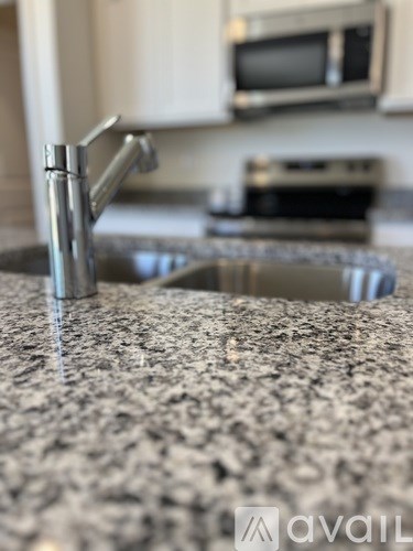 A kitchen sink with a granite counter top.