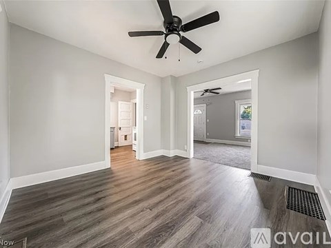 A spacious room with a ceiling fan and hardwood flooring.