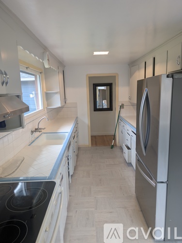 A kitchen with a stove top oven, a refrigerator, and a sink.