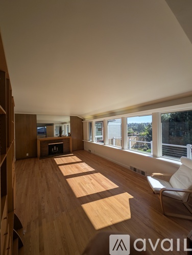A room with wooden floors and a large window with a view of trees.