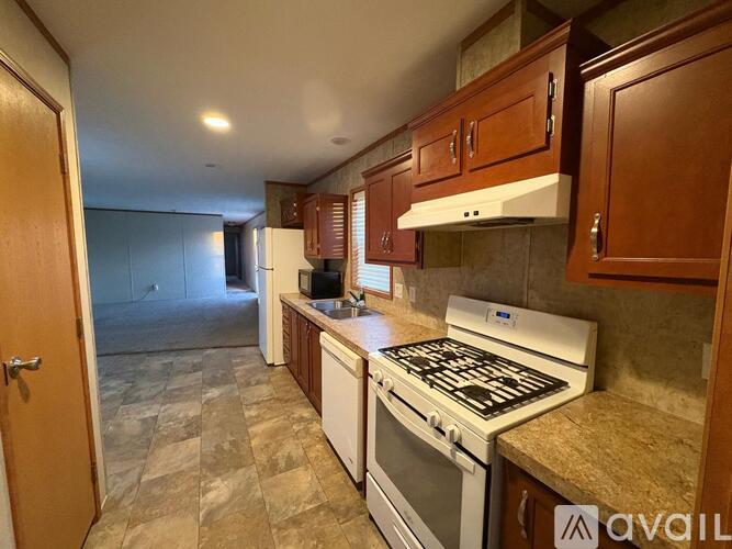 A kitchen with a white stove top oven and wooden cabinets.