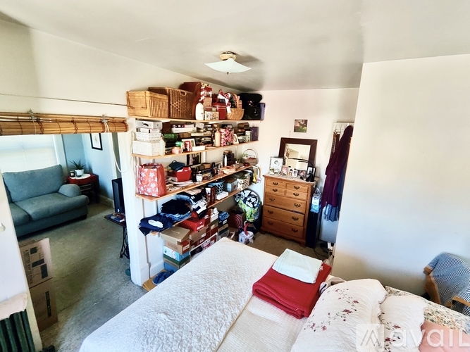 A bedroom with a bed, a couch, and a shelf with various items.