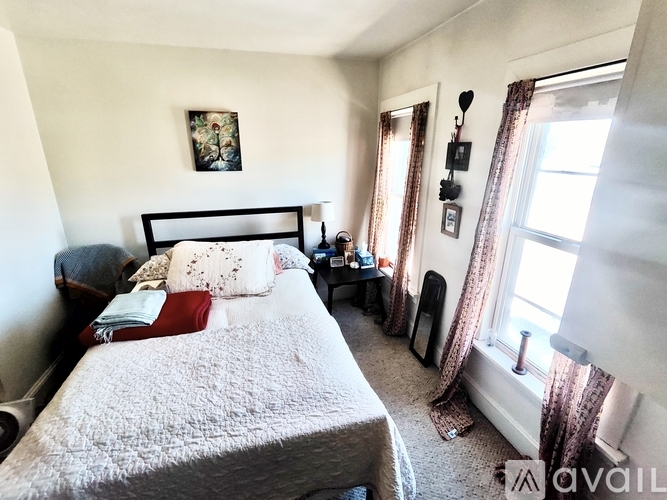 A bedroom with a bed, nightstand, and window.