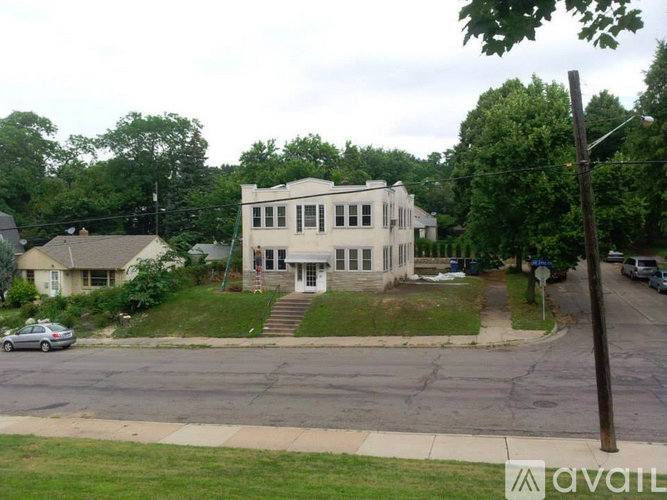 A white two-story house with a porch and a car parked in front.