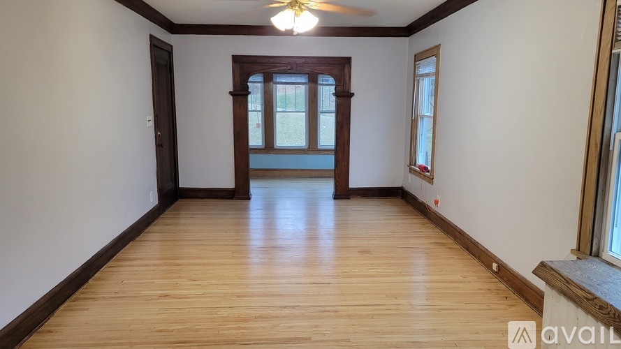 A room with wooden floors and a window with a view of a building outside.
