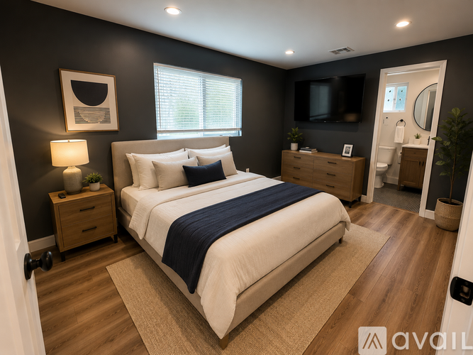 A well-lit bedroom with a large bed and a television.