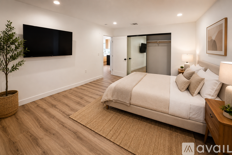 A bedroom with a large bed, a flat screen TV, and a plant.