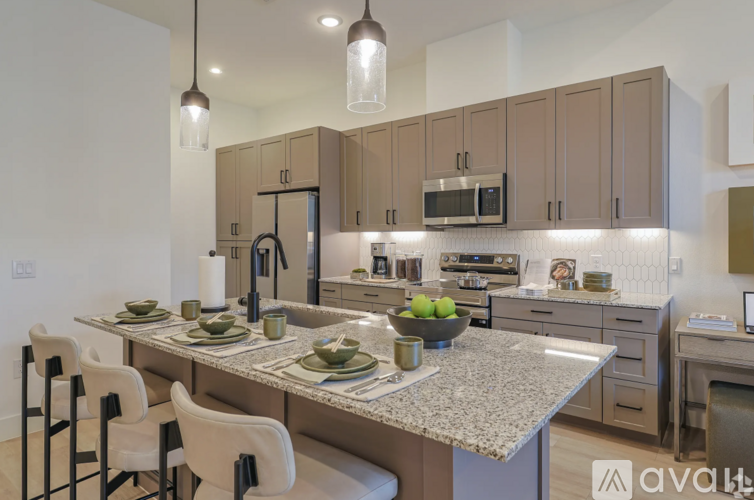A kitchen with a table set for two and a bowl of fruit on the counter.