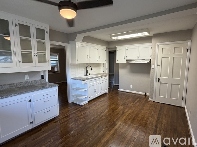 A kitchen with white cabinets and a wooden floor.