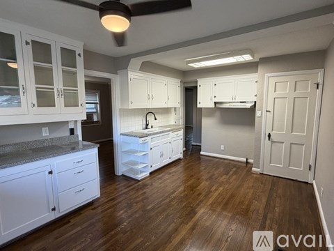 A kitchen with white cabinets and a wooden floor.