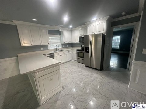 A kitchen with white cabinets and marble flooring.
