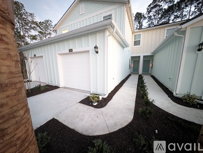 A white house with a garage door and a small garden in front.