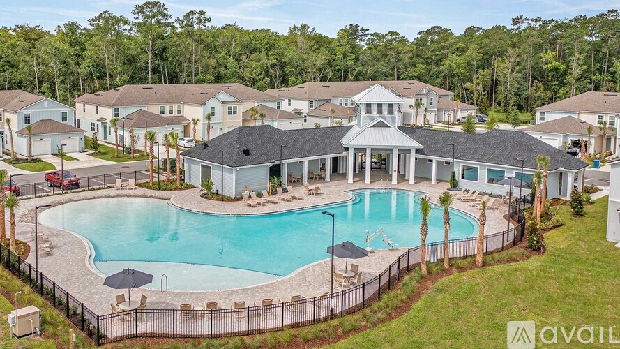 A large swimming pool surrounded by a fence and a few lounge chairs.