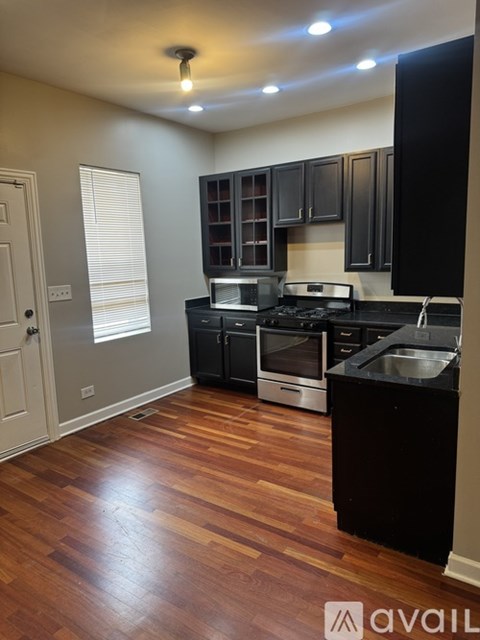 A kitchen with wooden floors and black countertops.