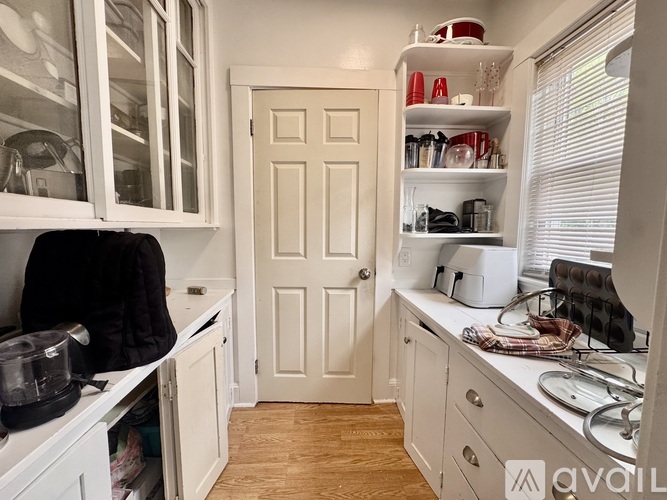 A kitchen with white cabinets and a white door.