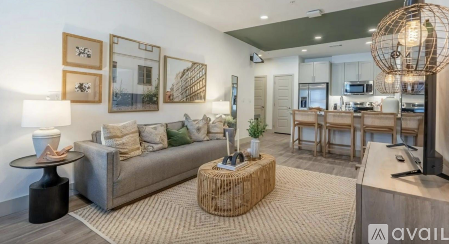 A modern living room with a grey sofa, a woven coffee table, and a large globe light fixture.