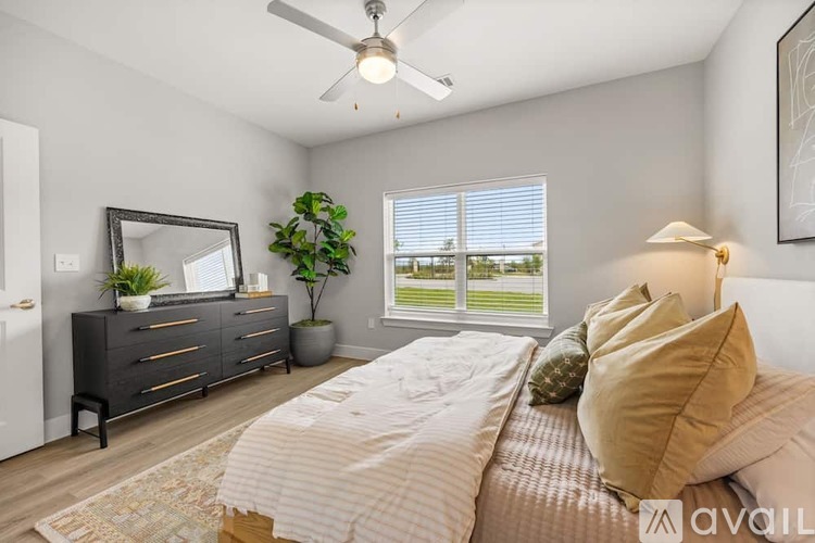 A bedroom with a large bed, a dresser, and a ceiling fan.