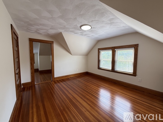 A room with wooden floors and a window with a view of trees.