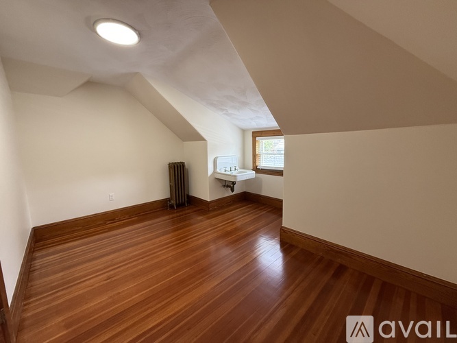 A spacious room with wooden floors and white walls.