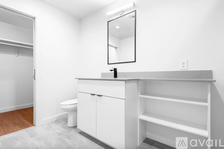 A white bathroom with a toilet, sink, and mirror.