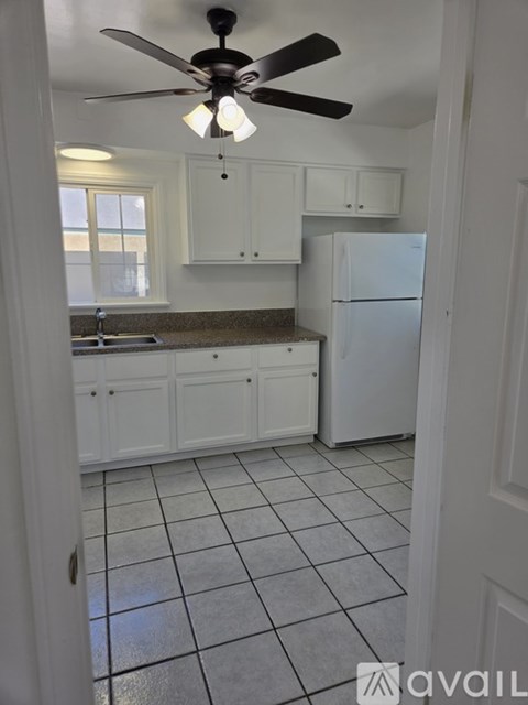 A kitchen with white cabinets and a white refrigerator.