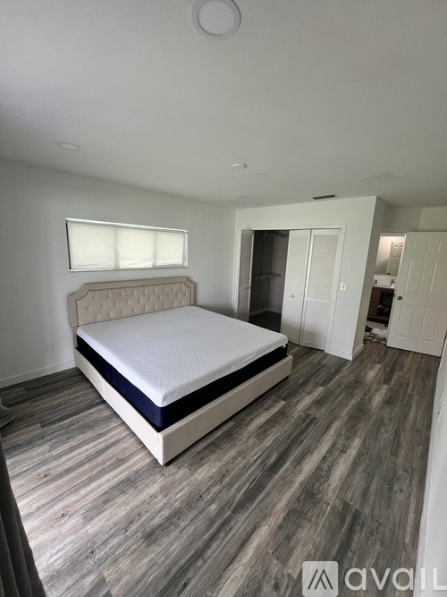 A bedroom with a large bed and wooden flooring.