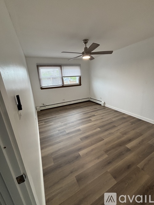 A room with a ceiling fan and a window with blinds.