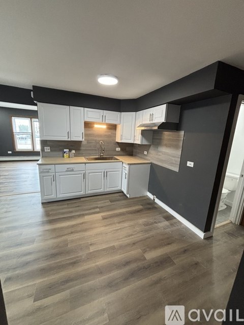 A kitchen with white cabinets and a wooden floor.