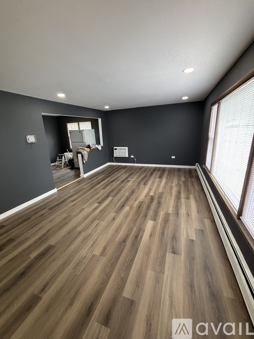 A room with wooden flooring and a window with blinds.