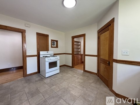 A kitchen with a white stove top oven and a tiled floor.