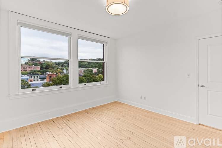 A room with wooden floors and two windows overlooking a cityscape.