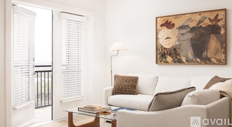 A living room with a couch, a coffee table, and a painting on the wall.