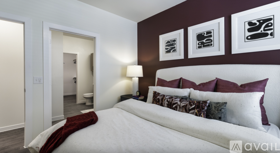 A bedroom with a large bed and three framed pictures on the wall.