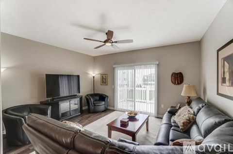 A living room with a brown leather couch and a television.