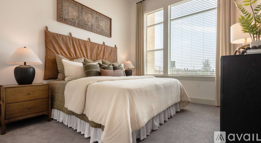 A bedroom with a large bed and a lamp on a nightstand.