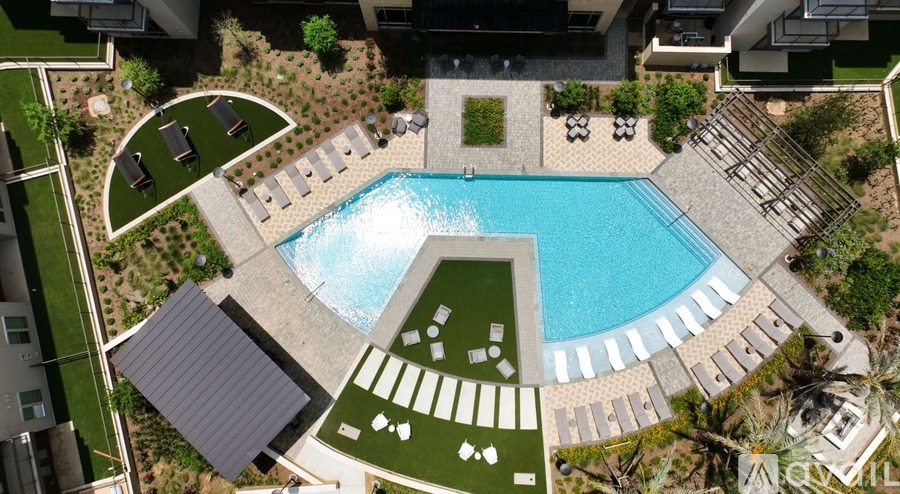 A large swimming pool surrounded by a patio and lawn.