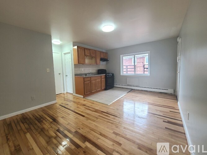A room with wooden flooring and a window with red curtains.